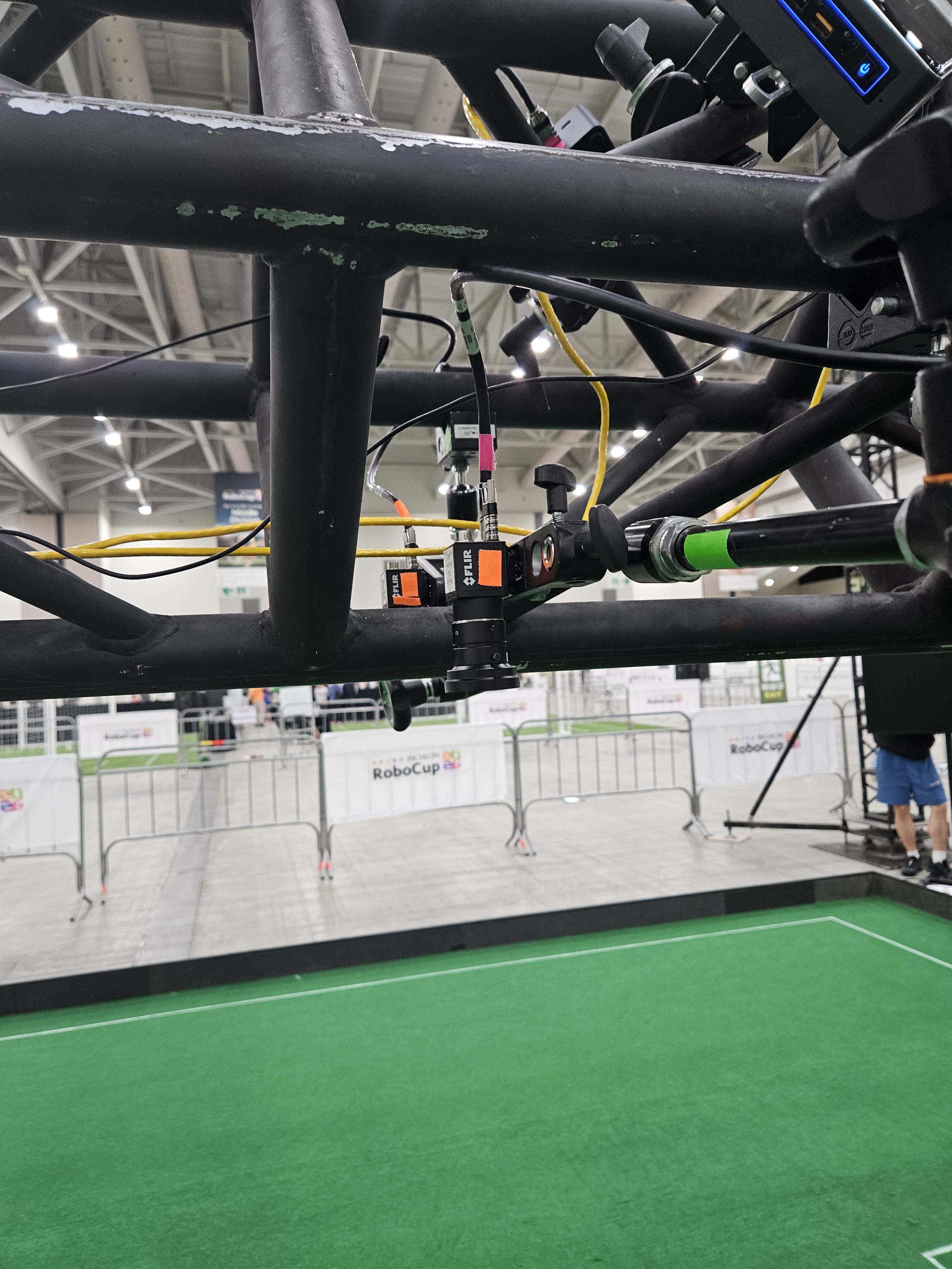 Two cameras in a redundant configuration on a Division A truss at Incheon 2026, with colored tape on the cameras, cables, and mounting arms